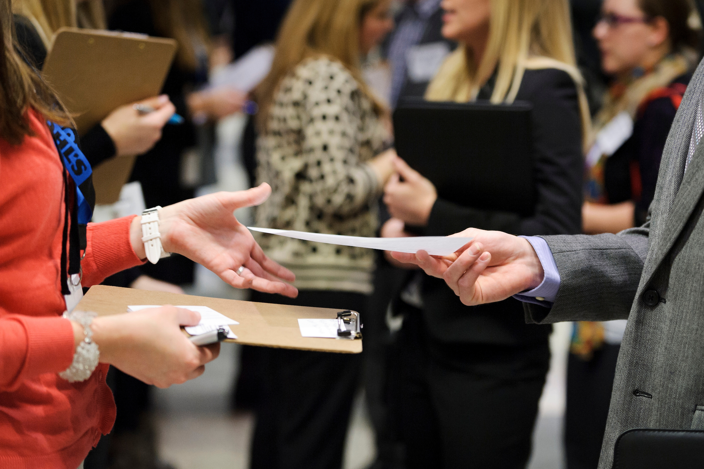 One person hands another a piece paper while at a career fair